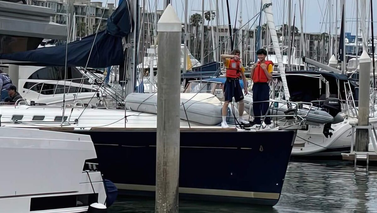 Kids working on the bow of a sailboat.