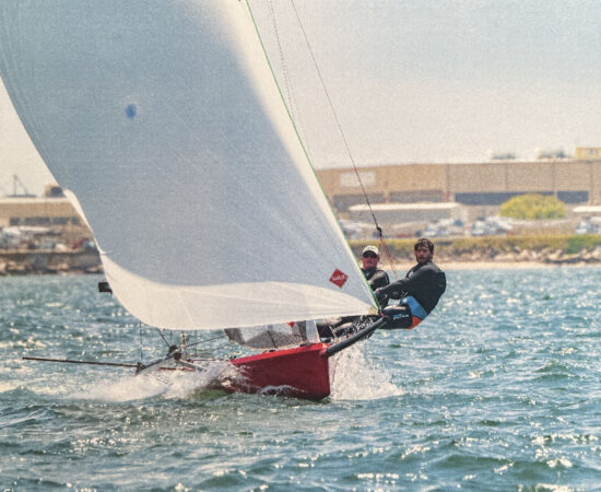 Two people hiking out on a sailboat.