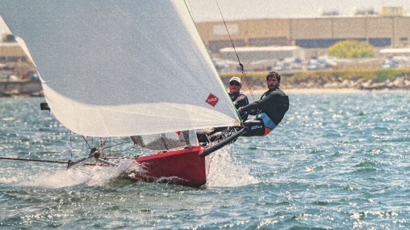 Two people hiking out on a sailboat.