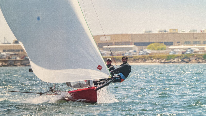 Two people hiking out on a sailboat.