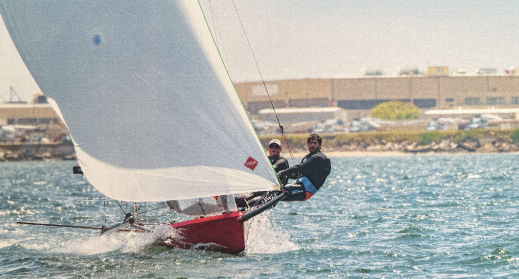 Two people hiking out on a sailboat.