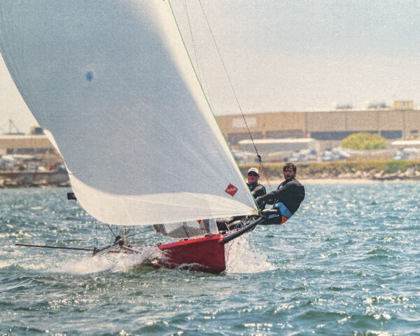 Two people hiking out on a sailboat.
