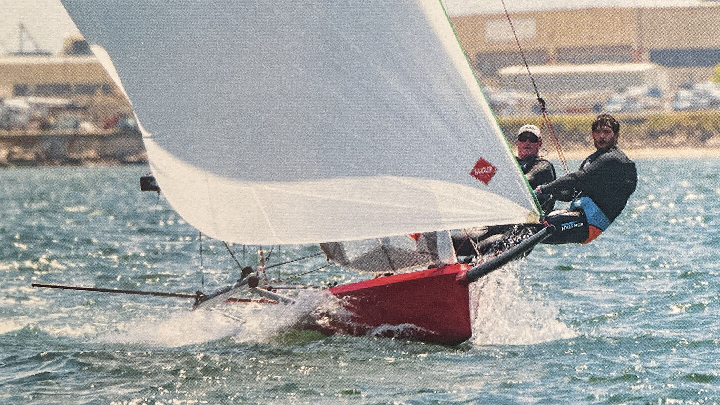 Two people hiking out on a sailboat.