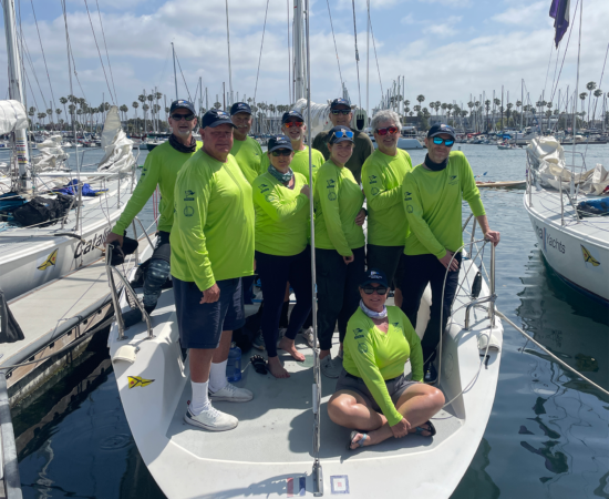 Ten sailboat racers pose on their race boat.