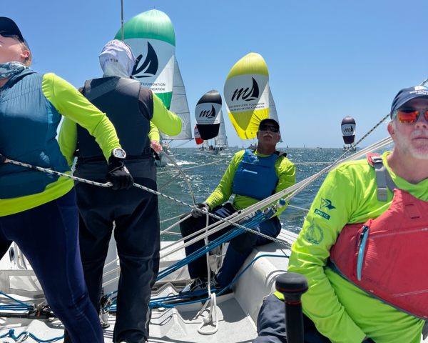 Sailors sailing downwind, flying the spinnaker, ahead of all the other boats