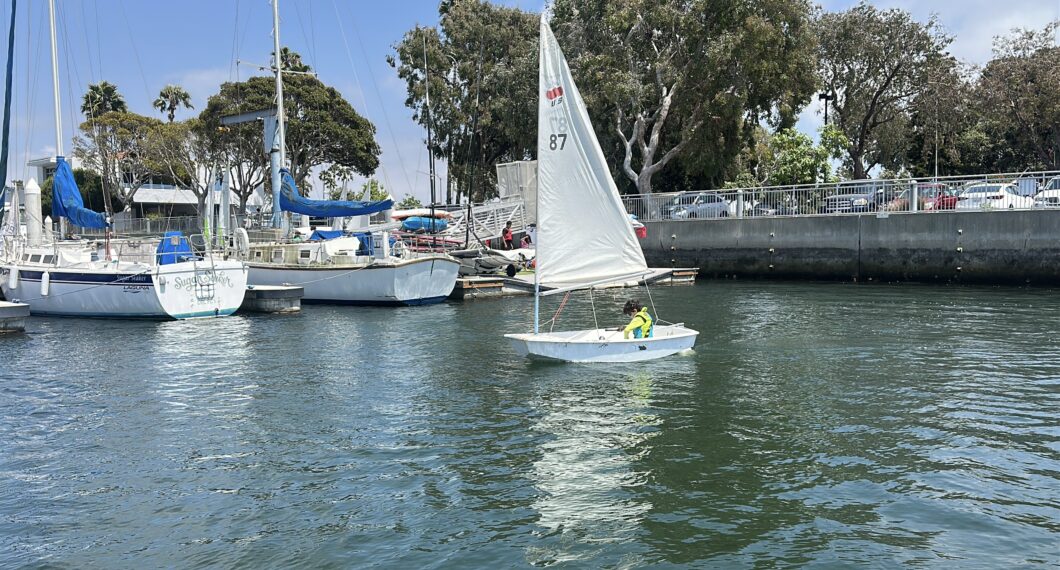 Boy sailing a dinghy in the marina