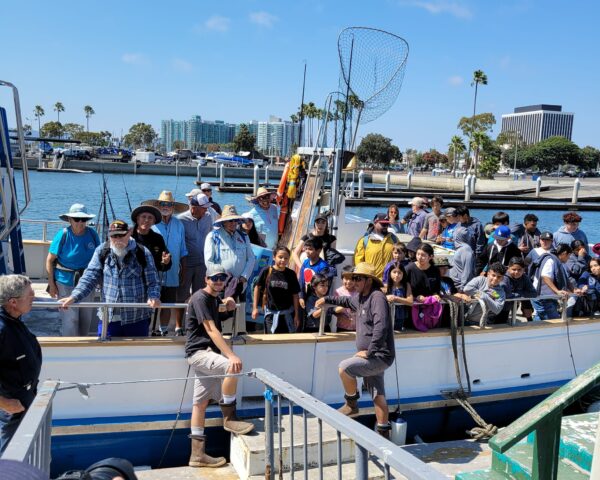 A group of kids on a boat with fishing gear