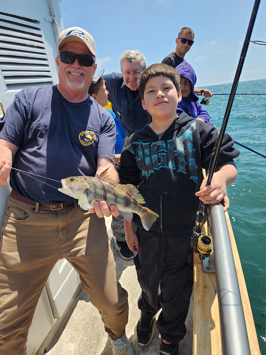 Everyone is all smiles as a boy shows off the fish he caught