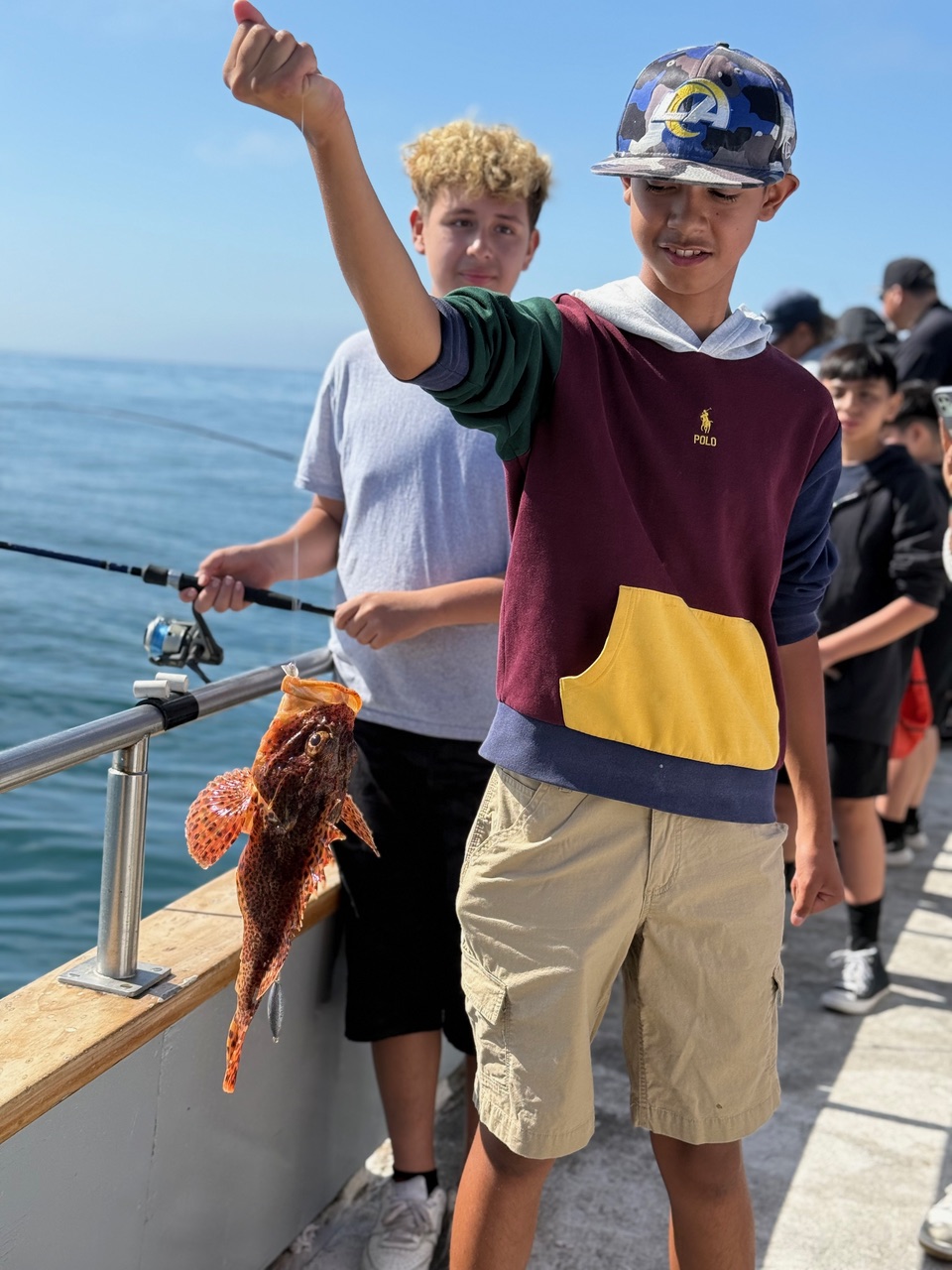 Happy youth holds up the fish he caught
