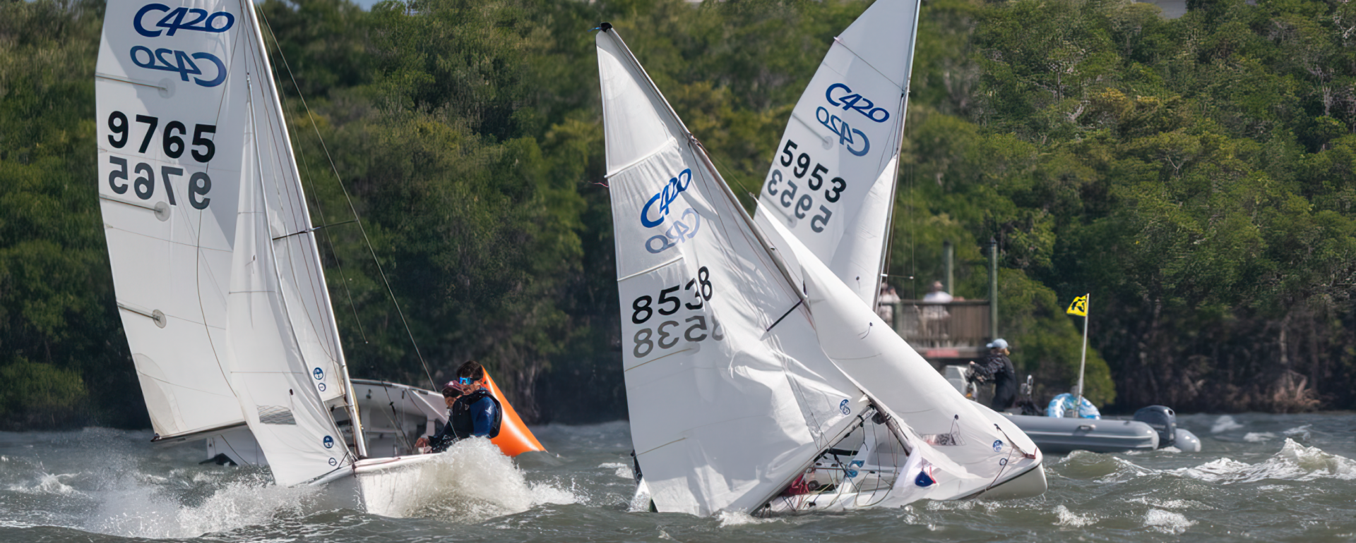 Three sailboats in close quarters, rounding the mark in heavy breeze.