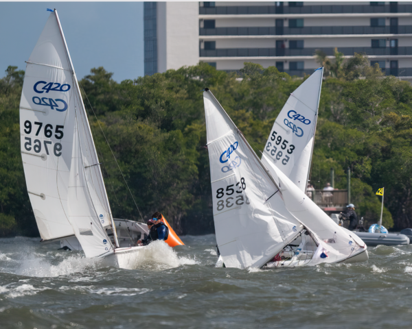 Three sailboats in close quarters, rounding the mark in heavy breeze.