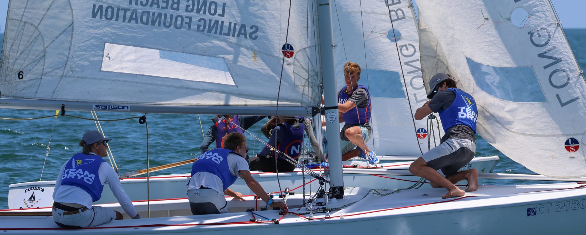 Three young men racing on a sailboat with 